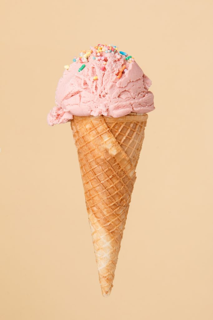 cornet ice cream with a strawberry scoop on a colorful backgroun