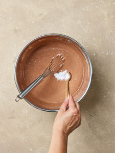 adding baking soda in a bowl of chocolate cake dough, top view