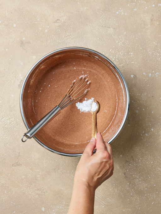 adding baking soda in a bowl of chocolate cake dough, top view