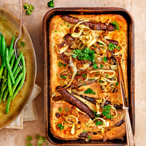 Toad in de hole met chipolata, worchestershire-uien en gebakken sperziebonen