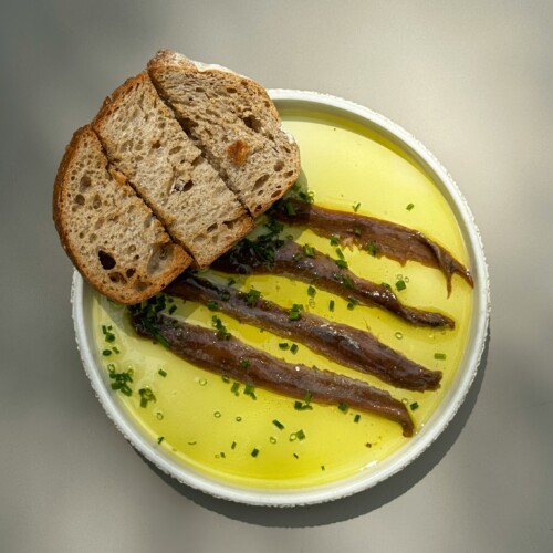 een bordje ansjovis met olie en brood